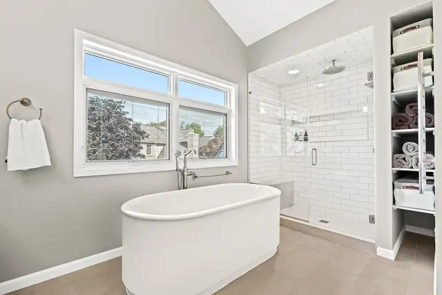 Primary bathroom with a freestanding soaking tub and a glass-enclosed shower lined in white subway tile