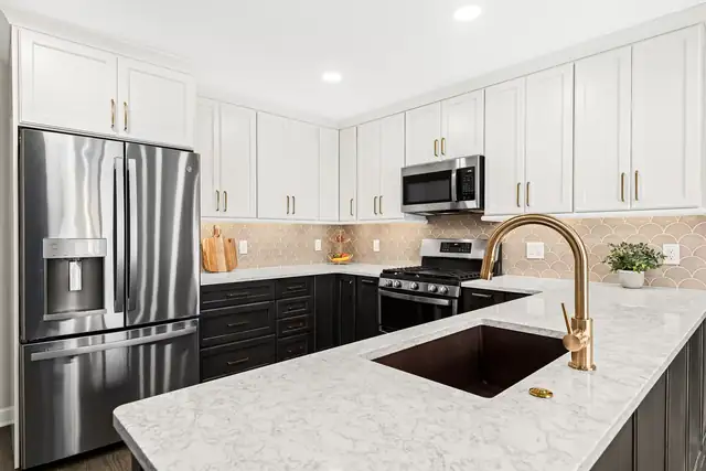 Canton, MI kitchen with white upper cabinets, dark base cabinets, white counters and a brass faucet
