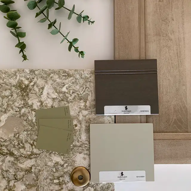 Mood board of kitchen remodeling material selections: granite sample, sage and gray cabinet door finishes and a brass knob